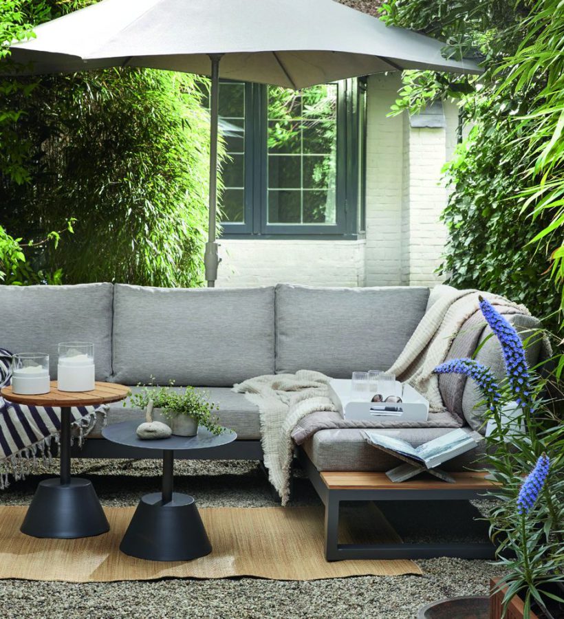 Hoekbank onder een parasol in een groene tuin