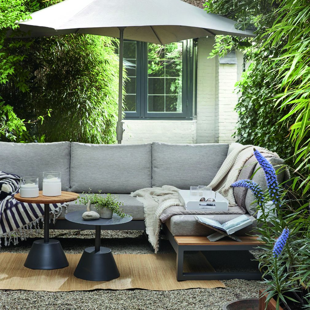 Hoekbank onder een parasol in een groene tuin