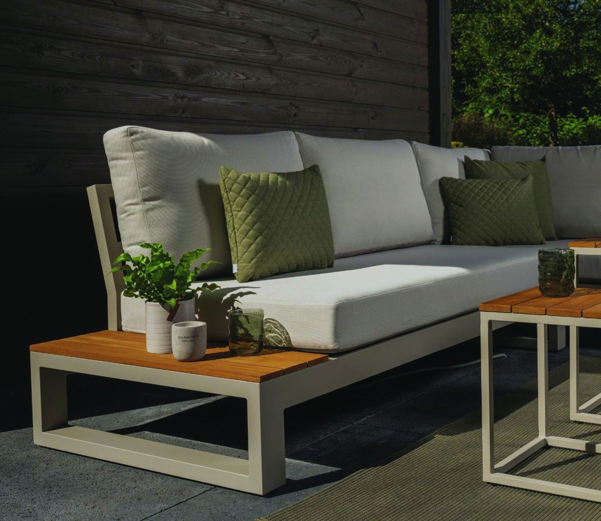 Lichte loungebank met teakhouten bijzettafel op een overdekt terras