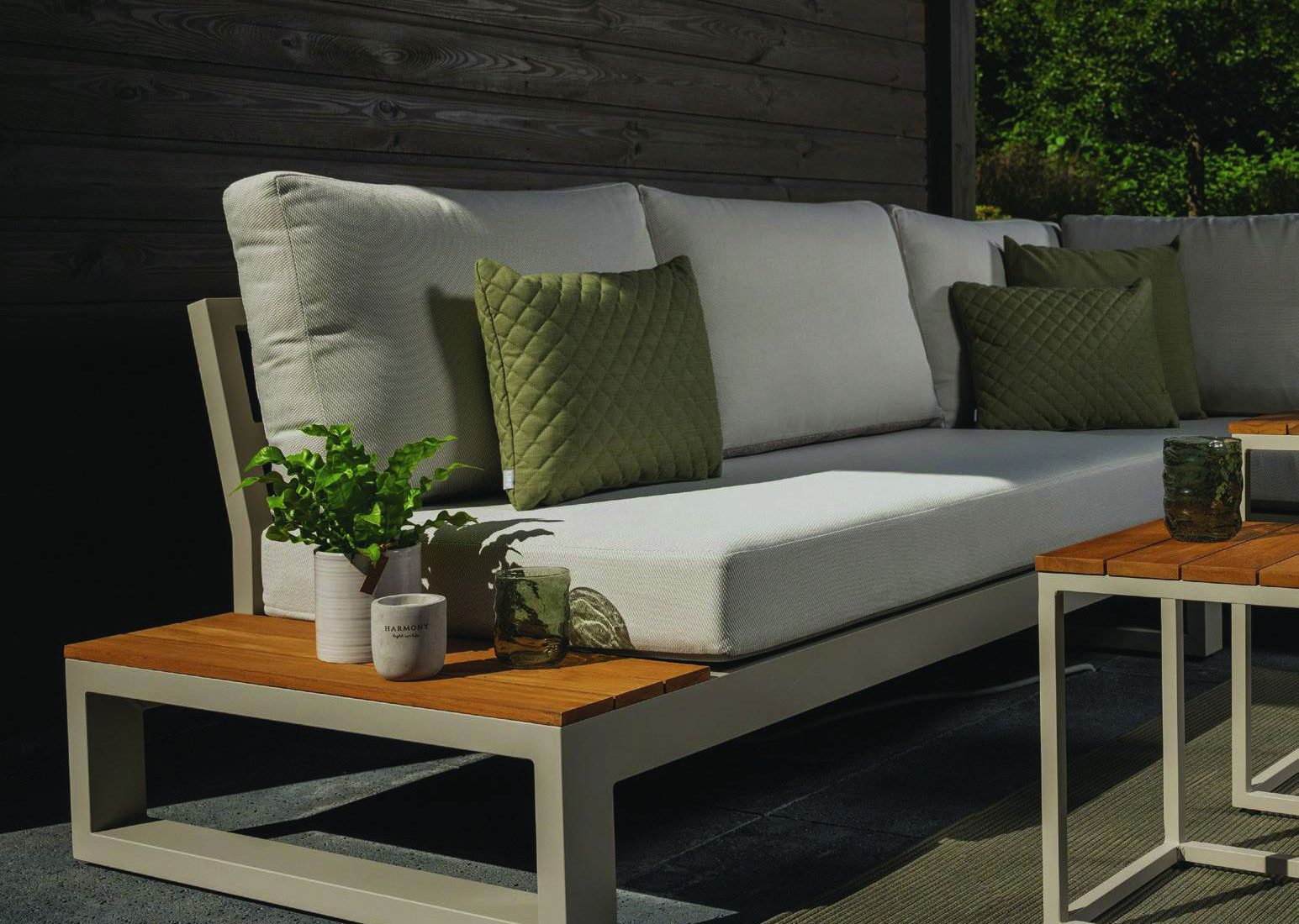 Lichte loungebank met teakhouten bijzettafel op een overdekt terras