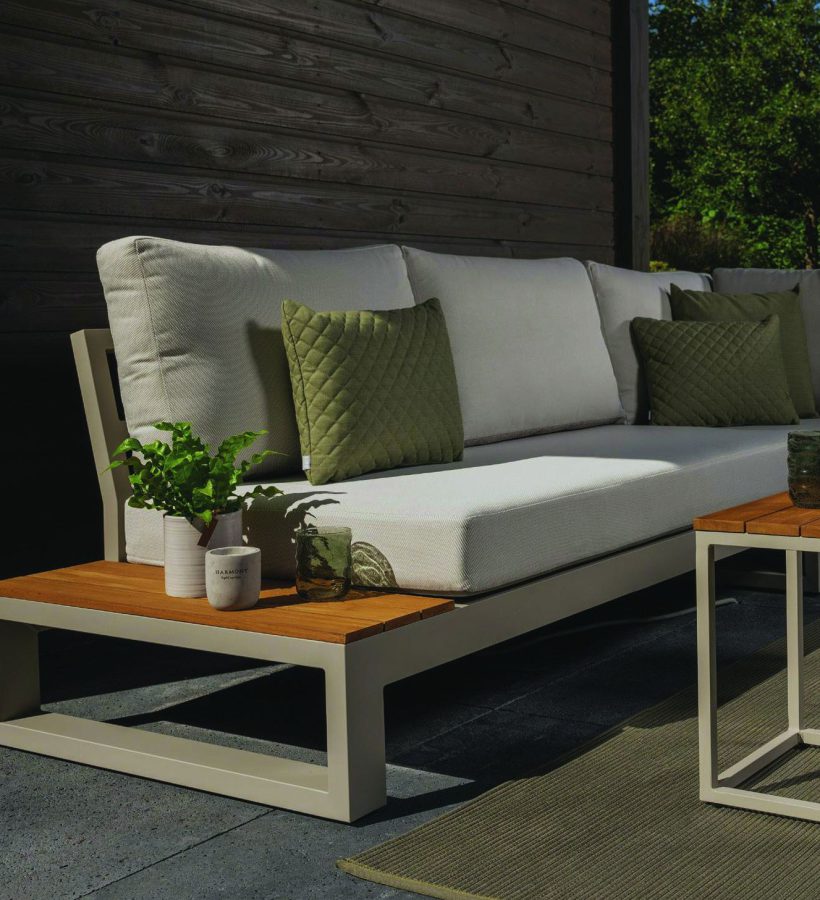 Lichte loungebank met teakhouten bijzettafel op een overdekt terras