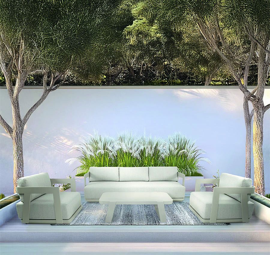 Lichte loungeset met salontafel op een terras met witte muur, bomen en siergrassen